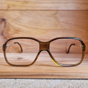 May include: A pair of brown plastic eyeglasses with a square frame and clear lenses.