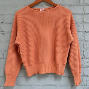 May include: An orange sweater with a ribbed knit design. The sweater features a crew neck, long sleeves, and ribbed cuffs and hem. The label shows the word "sunnyside".