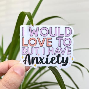 May include: White sticker with pink and peach lettering that reads "I would love to but I have anxiety". The sticker has small gold glitter stars around the text.