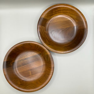 May include: Two wooden bowls, one slightly larger than the other, with a natural wood finish. The bowls have a unique design with a series of grooves running across the surface.