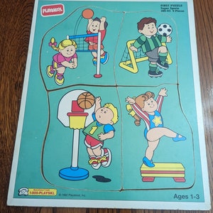 May include: A Playskool First Puzzle Super Sports 4-piece puzzle for ages 1-3. The puzzle features four different sports scenes with children playing basketball, volleyball, soccer, and gymnastics. The puzzle pieces are made of wood and have a colorful, cartoon-like design.