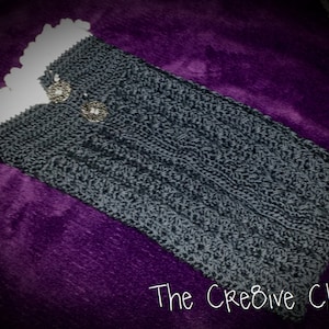 Puede incluir: Calentadores de piernas de color gris hechos a crochet con un borde de crochet blanco y dos botones plateados. Los calentadores de piernas están sobre una superficie morada. El texto "The Creative Chick" es visible en la esquina inferior derecha de la imagen.