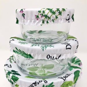 May include: Three glass bowls with white fabric lids featuring a green and white herb print. The lids have the names of the herbs printed on them: Basil, Rosemary, Oregano, Dill, Thyme, and Marjoram.