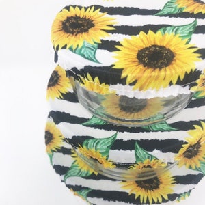 May include: Three reusable silicone food covers with a black and white striped background and a sunflower pattern. The covers are in different sizes and are stacked on top of each other.