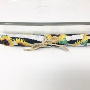 以下が含まれることがあります： ひまわり柄と白黒のストライプの布製のキッチンタオルが巻かれている。タオルは紐で結ばれている。