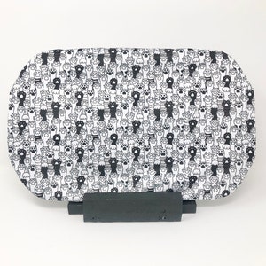 May include: A white oval tray with a black and white paw print pattern. The tray is on a black stand.