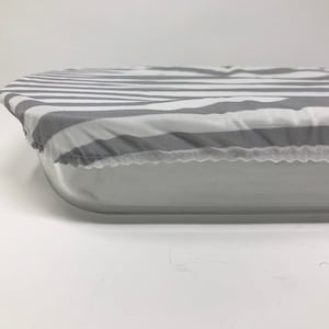 以下が含まれることがあります： 長方形のベーキングディッシュ用のグレーとホワイトのストライプのファブリックカバー。カバーは柔らかく通気性の良い素材で作られており、縫い付けられた縁があります。