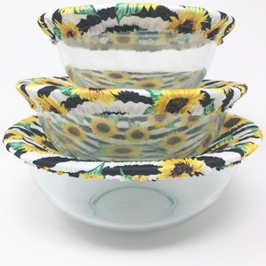 May include: Three reusable bowl covers with a sunflower and zebra stripe pattern. The covers are made of fabric and are designed to fit over bowls to keep food fresh.