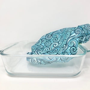 May include: A blue and black patterned fabric is draped over a clear glass baking dish.