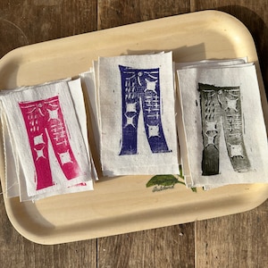 May include: Three fabric patches with a printed design of jeans in different colors: pink, blue, and green.