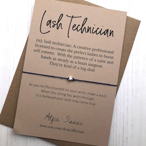 Puede incluir: Una tarjeta marrón con el texto "Lash Technician (n): lash technician: A creative professional licensed to create the perfect lashes to boost self esteem. With the patience of a saint and hands as steady as a brain surgeon. They're kind of a big deal" y un brazalete de cuerda negro con un dije de estrella plateada. La tarjeta también tiene el texto "As you tie this bracelet on your wrist, make a wish. When the string has worn through, it is believed your wish may come true." y el texto "Alfie Isaac www.etsy.com/shop/alfieisaac".
