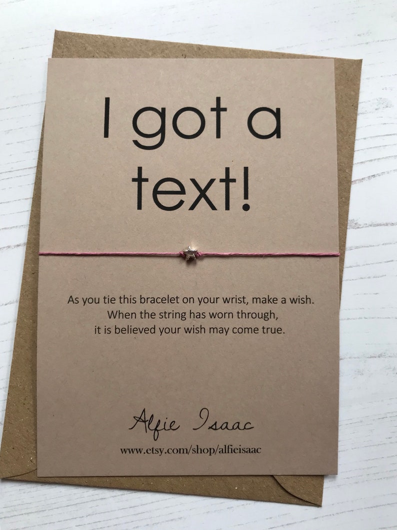May include: A greeting card with the text "I got a text!" in black font. A pink string bracelet with a star charm is attached. The card includes a wish-making message and the Etsy shop name.