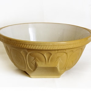 Puede incluir: Un cuenco mezclador vintage de color marrón claro con interior crema. El exterior presenta patrones florales en relieve y un borde texturizado. Este cuenco de cerámica es ideal para hornear y preparar alimentos.