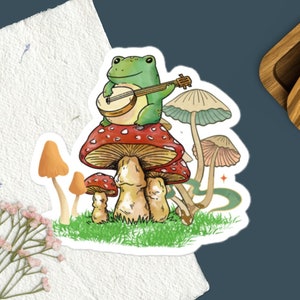 Frog Playing Instrument On Mushroom Sticker, Cottagecore Aesthetic, Nature Lover, Mushroom Sticker, Botanical, Frog Sticker
