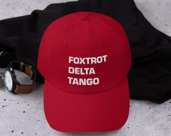 Gorra FOXTROT DELTA TANGO – Gorra bordada de papá con mensaje codificado anti-Trump, ajustable en rojo o negro.