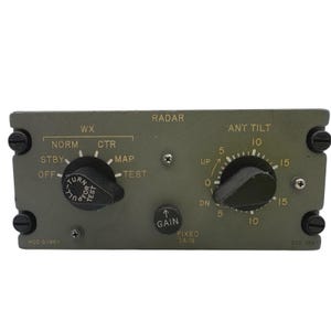 May include: An olive green rectangular radar control panel featuring two black rotary knobs and one smaller black gain knob. The panel includes labels for WX, ANT TILT, and GAIN, with text reading MOD G-1984 and OCT 426, secured by four black corner screws.