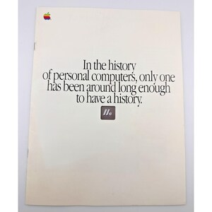May include: A vintage off-white Apple advertisement brochure featuring the rainbow-colored Apple logo in the top left corner. The text reads: In the history of personal computers, only one has been around long enough to have a history. Below is a small IIe logo.