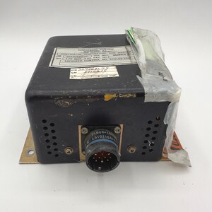 May include: A black Sundstrand Aviation controller for a side window temperature system. The unit features a metal base, a circular multi-pin connector, and a white identification label with text including P/N 26930889-01 and WT 1.70 MAX LBS.