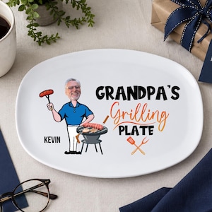 Könnte beinhalten: Weiße ovale Platte mit dem Text "GRANDPA'S Grilling PLATE" und einer Cartoon-Illustration eines grillenden Mannes. Die Platte hat ein Vatertags-Thema und enthält den Namen "Kevin".