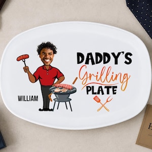 Könnte beinhalten: Weiße ovale Platte mit dem Text "DADDY'S Grilling PLATE" und einer Cartoon-Illustration eines grillenden Mannes. Der Mann trägt ein rotes Hemd und hält eine Wurst. Der Name "WILLIAM" steht darunter.