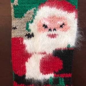 May include: A red, green, white, and black knitted stocking with a Santa Claus design. The stocking has a fuzzy white trim.