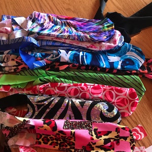 May include: A stack of colorful fabric scraps with various patterns, including zebra, leopard, and floral designs. The scraps are arranged in a pile on a wooden surface.