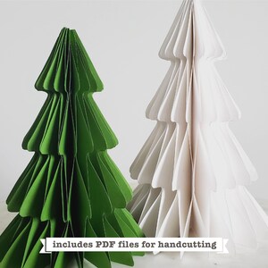 Puede incluir: Dos &aacute;rboles de Navidad de papel, uno verde y otro blanco, se muestran sobre una superficie de m&aacute;rmol. El texto "includes PDF files for handcutting" se muestra debajo de los &aacute;rboles.