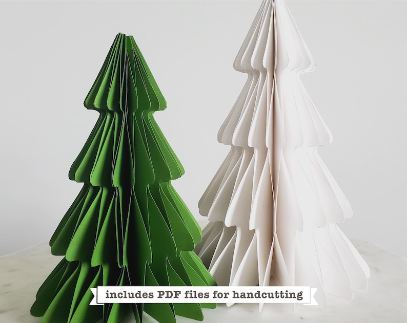 Puede incluir: Dos &aacute;rboles de Navidad de papel, uno verde y otro blanco, se muestran sobre una superficie de m&aacute;rmol. El texto "includes PDF files for handcutting" se muestra debajo de los &aacute;rboles.