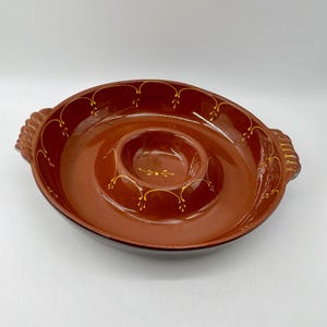 May include: A brown ceramic chip and dip serving dish. The dish has a circular design with a raised center for dip and handles on either side. The rim and center are decorated with gold accents.
