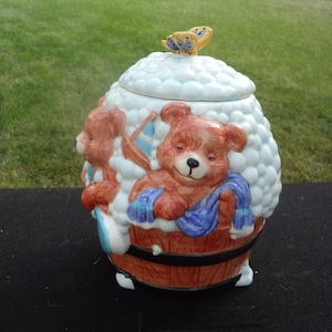 May include: Ceramic cookie jar with a blue and white butterfly on the lid. The jar features two brown teddy bears in a bathtub with blue and white bubbles.