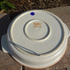 Pu&ograve; includere: Piatto da forno in ceramica bianca con due manici e un bordo marrone. Sul fondo del piatto &egrave; presente un adesivo dorato con la scritta "Treasure Craft - USA".