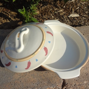 Pu&ograve; includere: Piatto da forno in ceramica bianca con coperchio. Il piatto e il coperchio sono decorati con peperoncini rossi e un bordo marrone e verde.