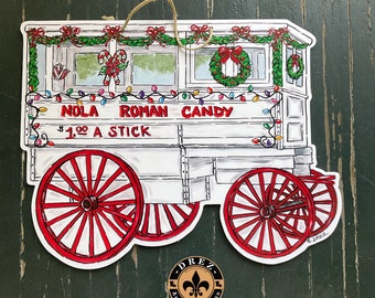 Könnte beinhalten: Ein weißer und roter Vintage-Wagen für Süßwaren mit einem Schild, auf dem "NOLA ROMAN CANDY 1,00 € PRO STANGE" steht. Der Wagen ist mit Weihnachtslichtern, Grünpflanzen und roten Schleifen verziert.