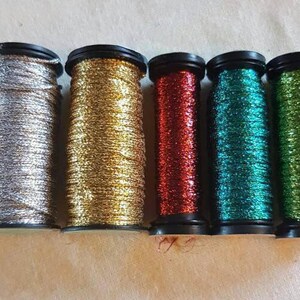 May include: Six spools of metallic thread in silver, gold, red, teal, and green.