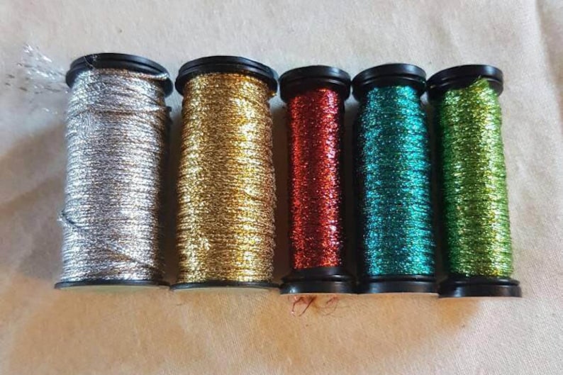 May include: Six spools of metallic thread in silver, gold, red, teal, and green.