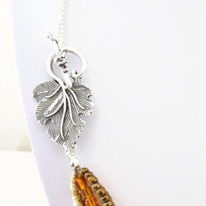 Op de afbeelding: Een meerstrengs ketting met een zilveren bladsluiting. De ketting heeft vier strengen kralen in tinten bruin, oranje en cr&egrave;me.