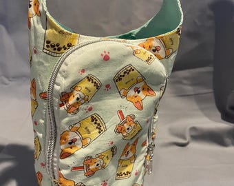 Op de afbeelding: Een lichtgroene stoffen tas met een herhaald patroon van corgi-honden en bubble tea. De tas heeft een zilveren rits, een witte riem en een mintgroene binnenkant. De tas is ontworpen om over de schouder te worden gedragen.