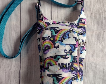 May include: A teal blue crossbody bag with a zipper closure. The bag is made of fabric with a unicorn, rainbow, and star pattern.