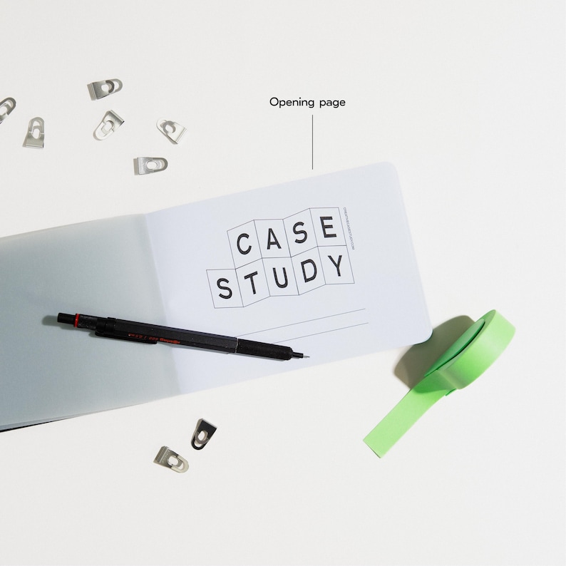 Peut inclure: Un cahier ouvert avec les mots "CASE STUDY" imprim&eacute;s sur la page. Un stylo noir, du ruban adh&eacute;sif vert et plusieurs trombones argent&eacute;s sont &eacute;galement sur la surface blanche. Le cahier est ouvert &agrave; la page d'ouverture.
