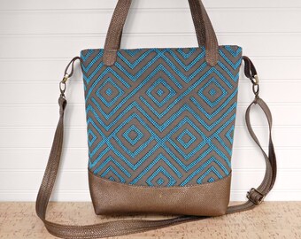 May include: A brown and blue tote bag with a geometric pattern. The bag has a long shoulder strap and a top handle.