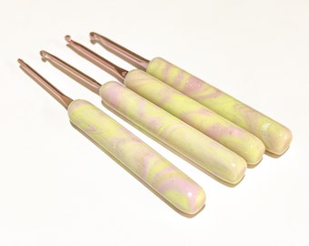 May include: Set of four crochet hooks with yellow and pink marbled handles and rose gold tips.