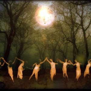 May include: A group of figures in white dresses dance in a misty woodland under a bright moon. The figures are silhouetted against the trees and the moon.