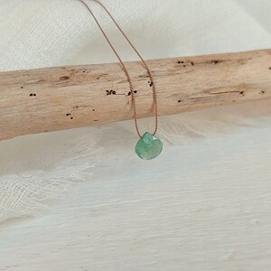 May include: A green gemstone pendant necklace on a brown cord.