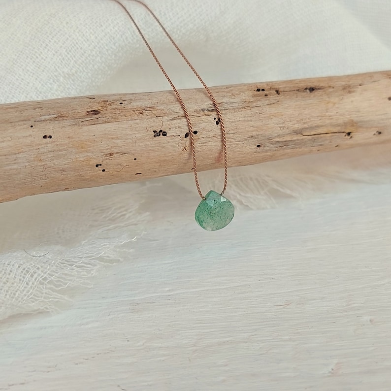 May include: A green gemstone pendant necklace on a brown cord.