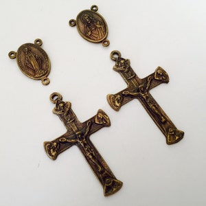 Puede incluir: Dos crucifijos de metal dorado antiguo con una figura de Jesucristo en la cruz. Cada crucifijo tiene un pequeño colgante ovalado con una figura religiosa.