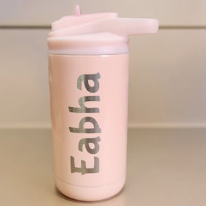 Puede incluir: Una botella de agua de acero inoxidable rosa con tapa de pajita. La botella tiene el nombre "Eabha" grabado en el lateral.