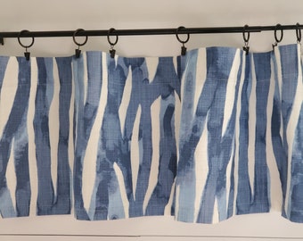 May include: Blue and white patterned valance with a modern abstract design. The valance is made of a soft, textured fabric and hangs from a black metal rod.