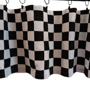 May include: A black and white checkered curtain panel. The fabric is hung from a rod with metal rings. The pattern is a classic racing flag design, with alternating black and white squares.