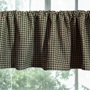 May include: A valance curtain with a green and beige checkered pattern. The fabric is gathered at the top, creating soft folds. The curtain hangs in front of a window, with a blurred outdoor scene visible through the glass.