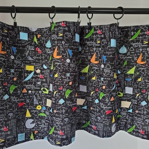 May include: Black and white fabric with a pattern of mathematical equations, geometric shapes, and symbols. The fabric is in the form of a curtain with a black rod at the top.